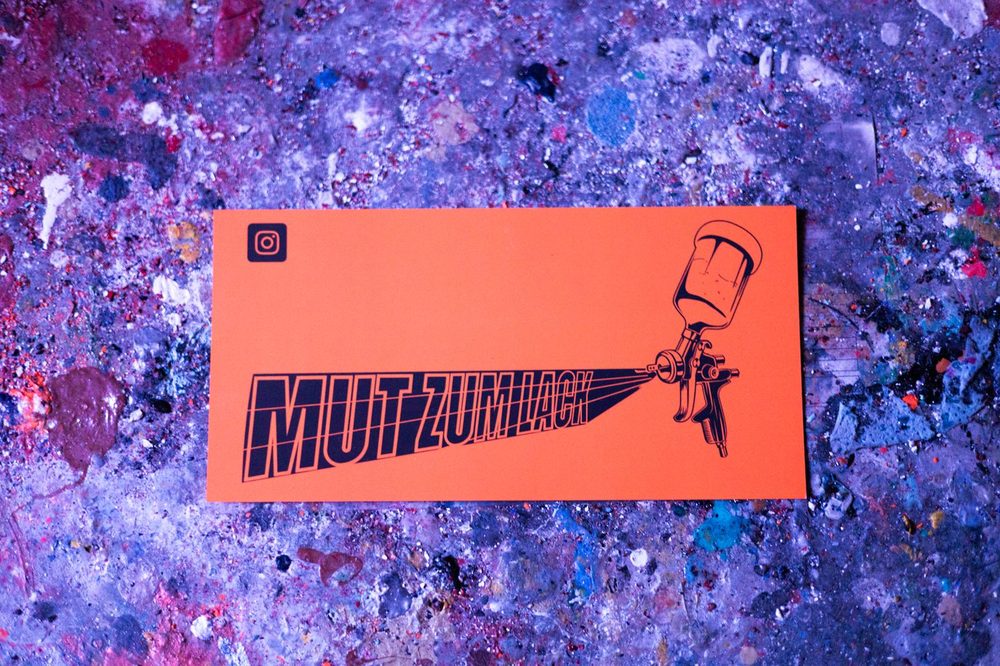 MUT ZUM LACK Logo-Grafik: Spritzpistole mit Schriftzug